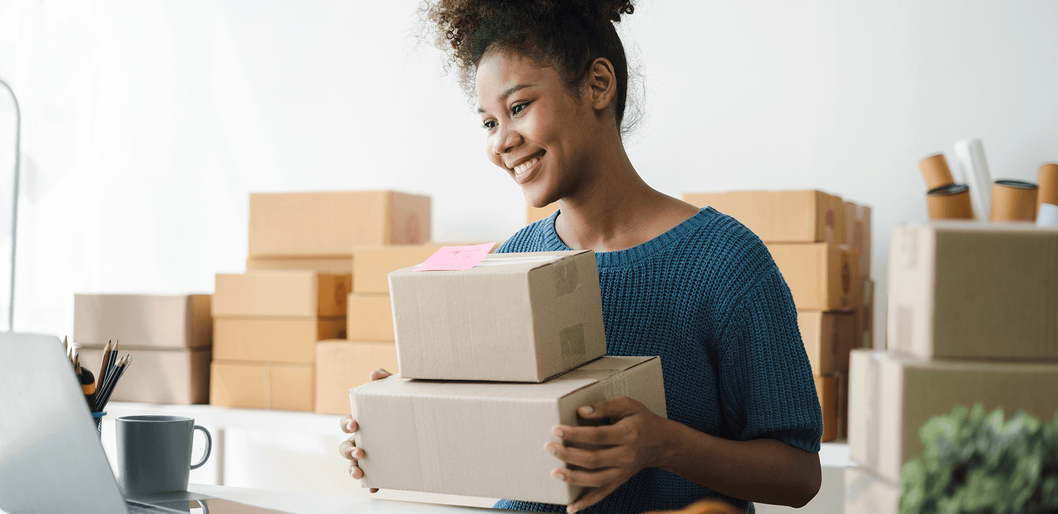 An image of a smiling woman packing boxes